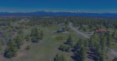 A scenic view of the Timber Ridge neighborhood in Pagosa Springs, Colorado, showcasing expansive open space, paved roads, and the majestic San Juan Mountains in the background.